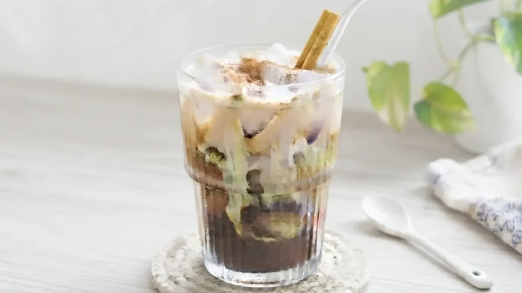 Chai spiced dirty cold brew topped with heavy cream and a dusting of cinnamon in a clear glass